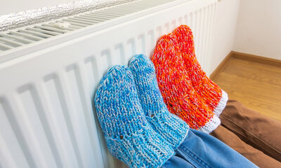 Foto van mensen die hun voeten warmen aan de radiator